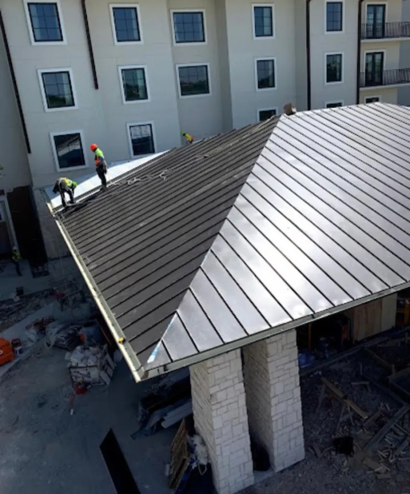 Crew installing standing seam metal roof panels on a commercial project in East Point